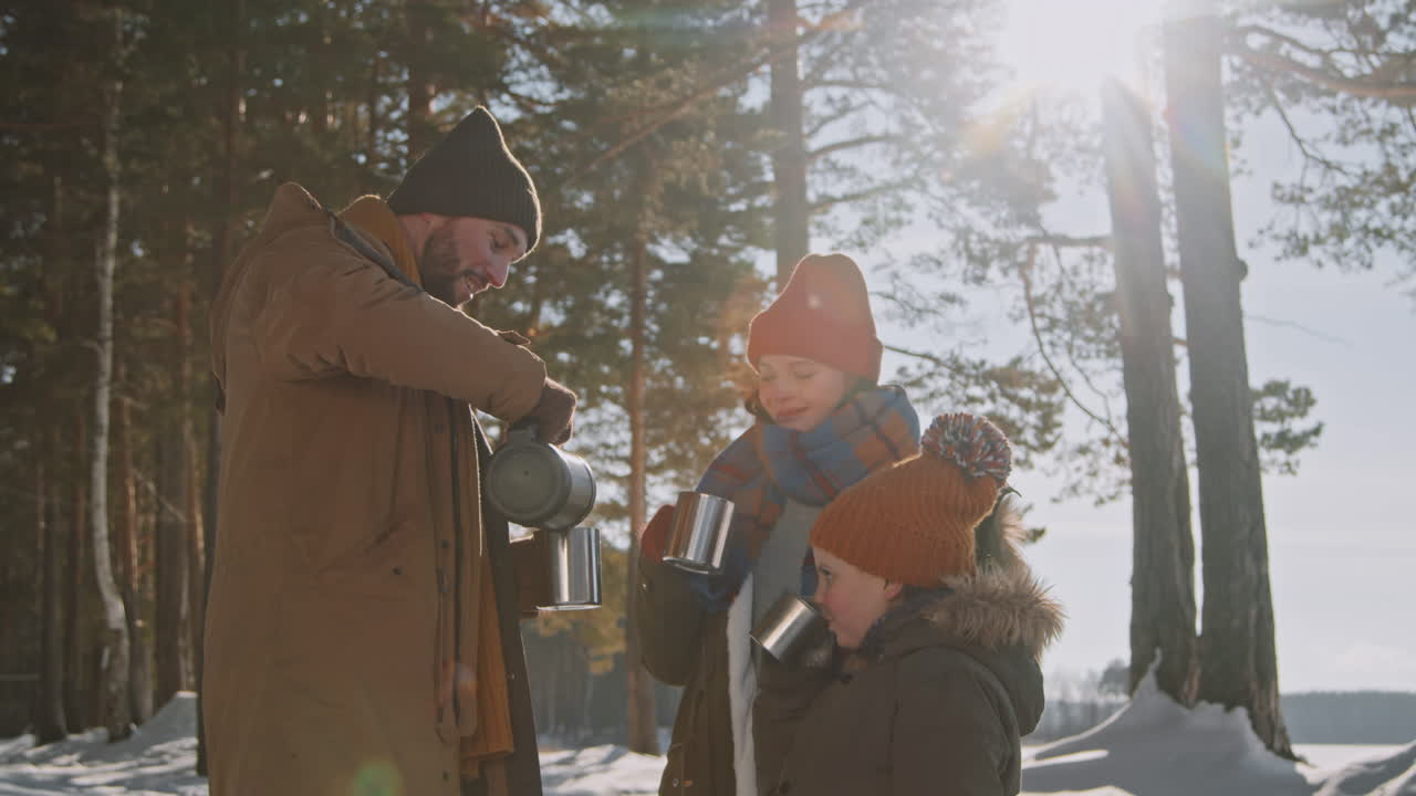 Perhe lämmittelee kuumalla teellä talvivaelluksella
