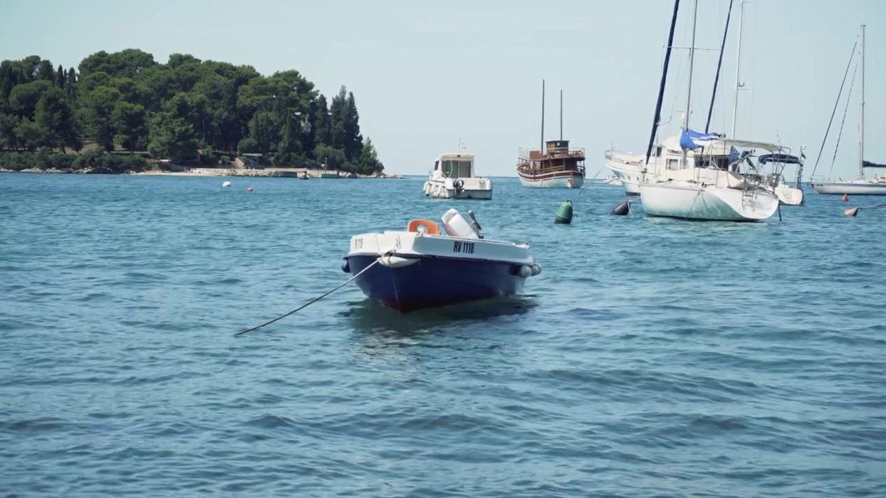 Una piccola barca galleggia pacificamente accanto ad altre barche in un piccolo porto.