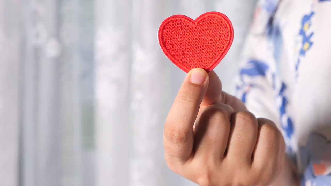 mano sosteniendo un corazón rojo