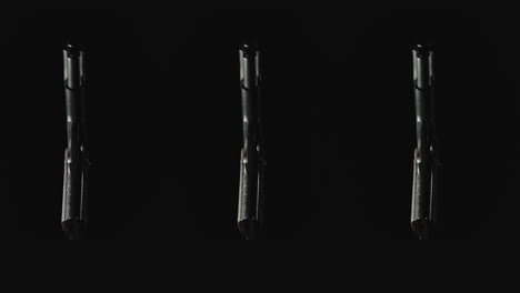 three pistols on the dark background rotate in slowmotion