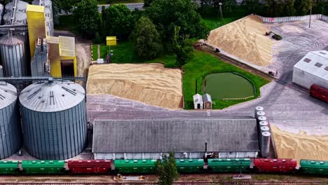 aerial footage of trains waiting at a warehouse to transport piles of grain
