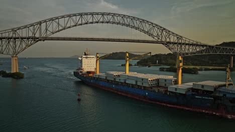 panama city aerial v51 cinematic low level fly around commercial cargo ship at puerto balboa capturing bridge of americas with glowing sun at sunset golden hours - shot with mavic 3 cine - march 2022