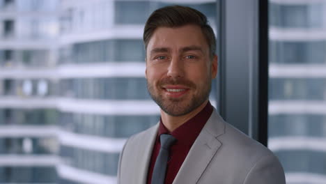 thinking caucasian businessman smiling looking camera in modern window office.