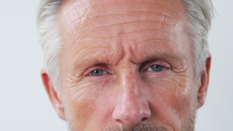 Close-Up-Studio-Shot-Of-Serious-Senior-Man-Against-White-Background-Looking-At-Camera