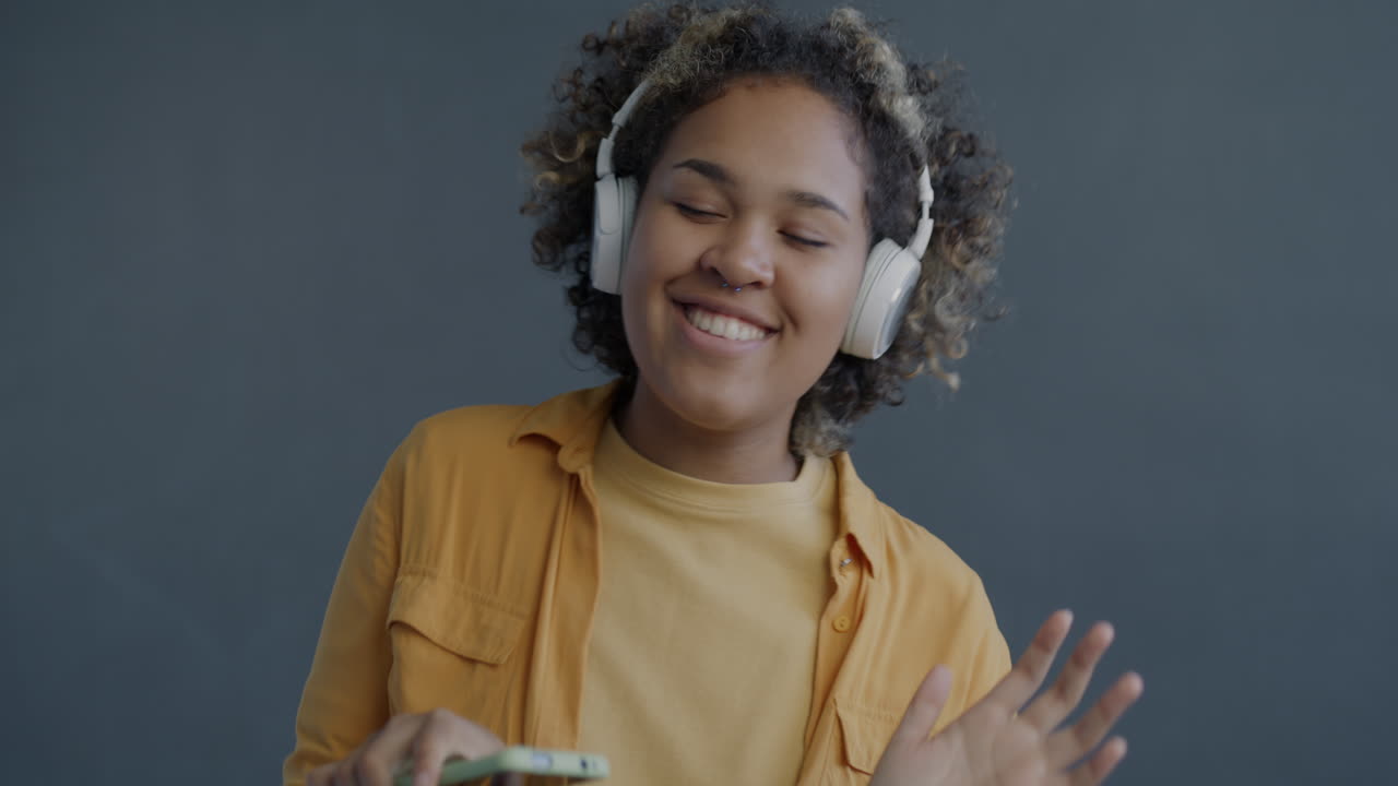 Happy woman dancing and listening to music on her phone