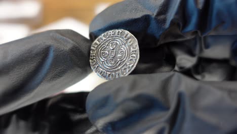 coleccionista examinando una moneda de oro portuguesa de la época medieval