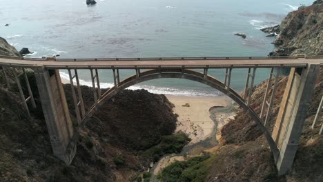 luftdrohnen-stockvideo der autobahn bixby bridge mit wasser und ufer unten in big sur, monterrey, kalifornien