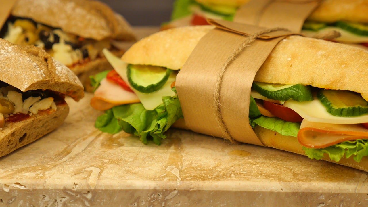 Freshly Prepared Baguette Sandwiches Wrapped in Paper on a Counter
