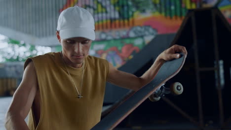 focused teenager repairing skate board at skate park graffiti background.