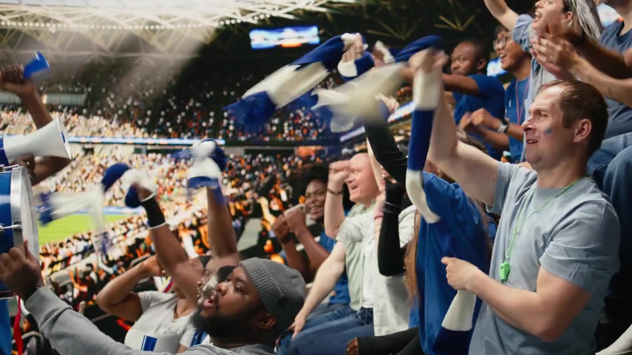 Diverse blue football supporters raising arms and chanting together