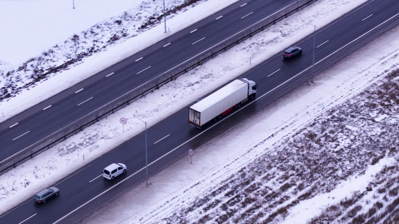 Un semirimorchio bianco che guida su una strada autostradale bagnata in inverno, vista aerea di inseguimento