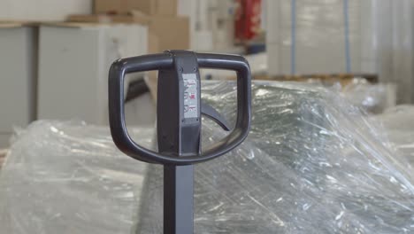 warehouse worker reaches into frame to pull hand truck handle, close