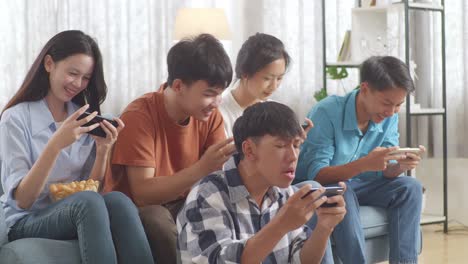 asian teenagers playing video games on smart phone at home. team win and team lost