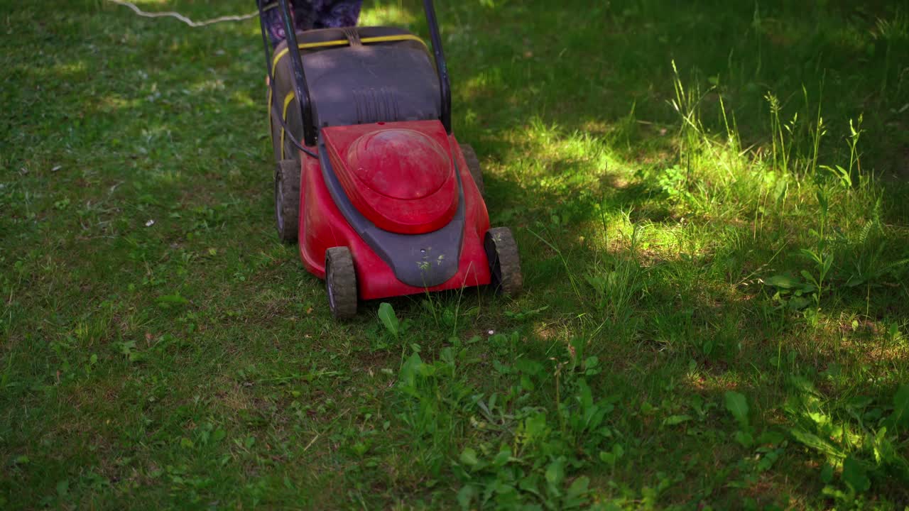 Gardening. Someone mows the grass with an electric lawn mower. Mowing the lawn grass. Landscaping the garden.