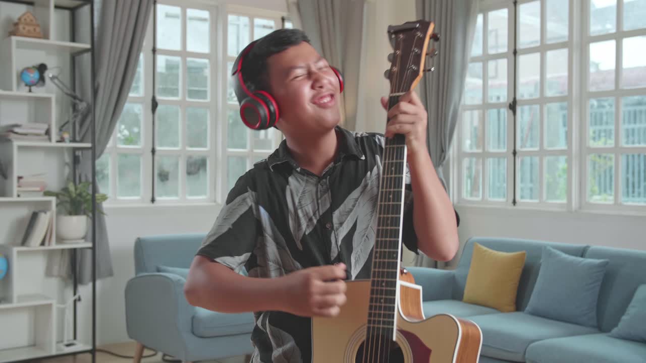 Funny Asian Boy Playing Guitar, Sing A Song And Dancing At Living Room