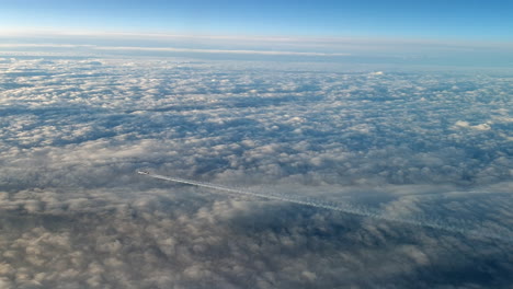 Incredible-view-from-the-cockpit-of-an-airplane-flying-high-above-the-clouds-leaving-a-long-white-condensation-vapour-air-trail-in-the-blue-sky