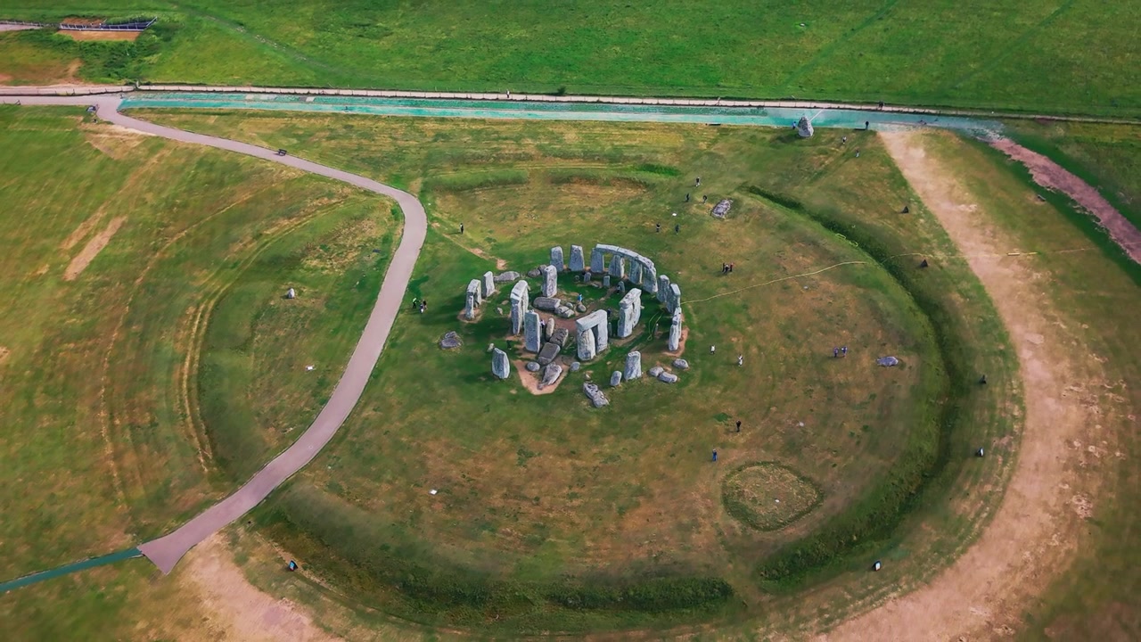 Drone-luftfoto af Stonehenge set ovenfra, der viser den gamle forhistoriske stencirkel, omkringliggende græsland, besøgsstier og mennesker i Wiltshire, England.