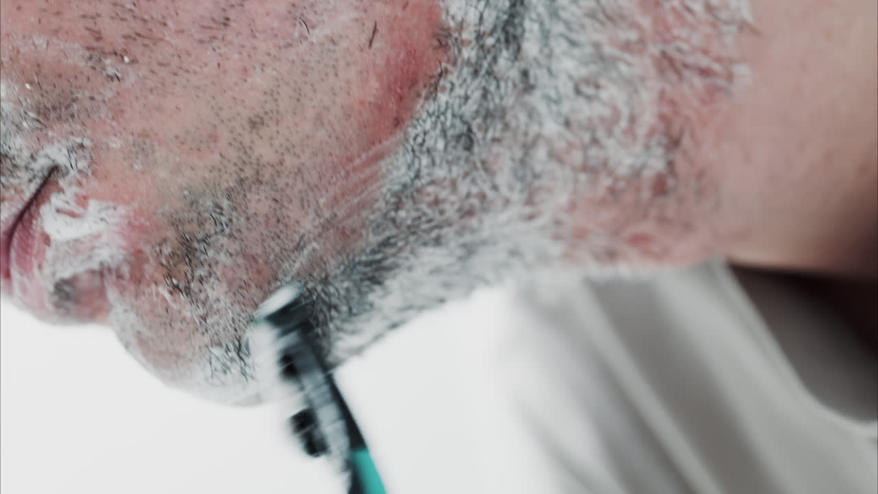 Primo piano di un uomo che si rade la barba con un rasoio