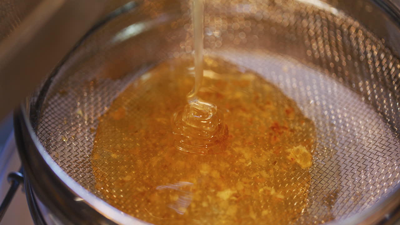 Miele dorato con consistenza di caramello versato attraverso un setaccio
