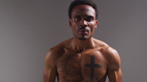 Real-Time-Studio-Portrait-Shot-Of-Tattooed-Male-Boxer-Warming-Up-Before-Boxing-Match-Against-Grey-Background