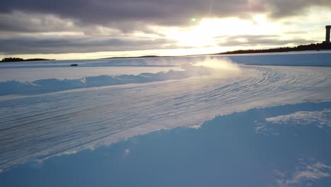 two sport cars drifting on frozen lake in finland during golden hour – aerial winter landscape with a frozen race track high speed low altitude
