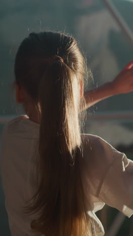 child plays standing by window at glamping. little girl has fun with multiple reflections under glass dome in hotel. creative kid in resort hotel