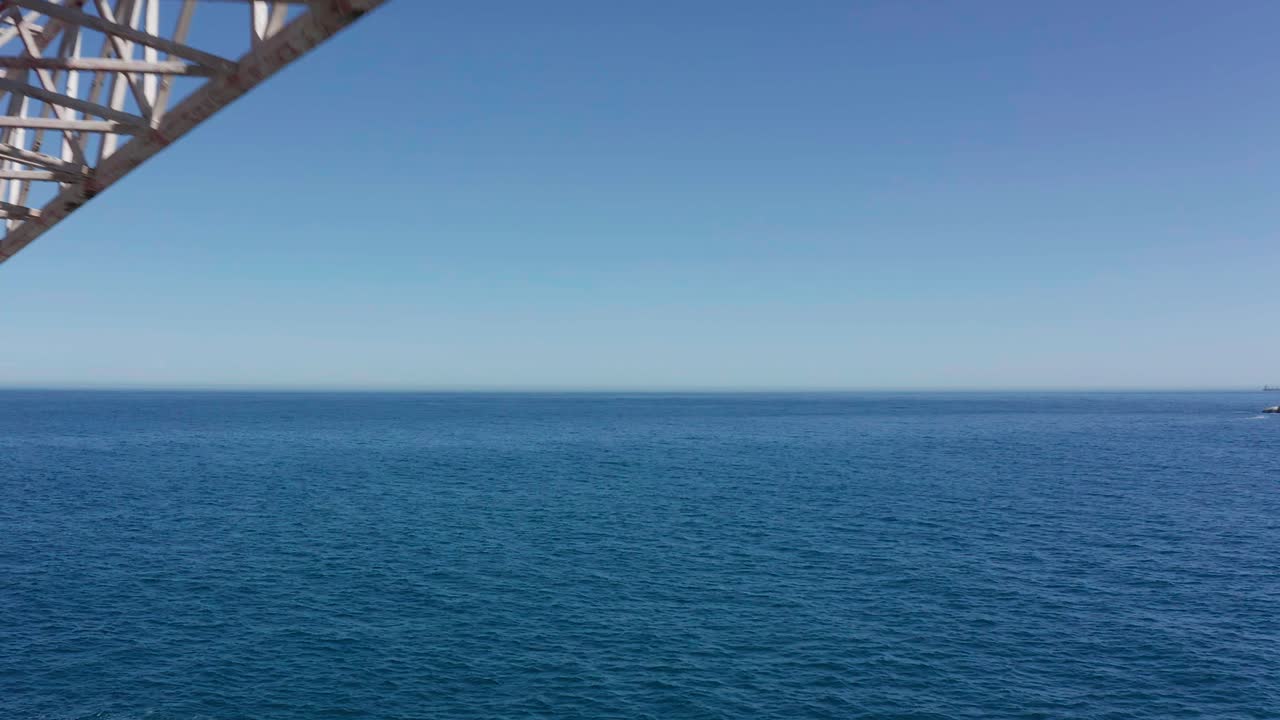 Moving aerial view close up of abandoned shipwreck with crane off rocky shoreline in Cape Town