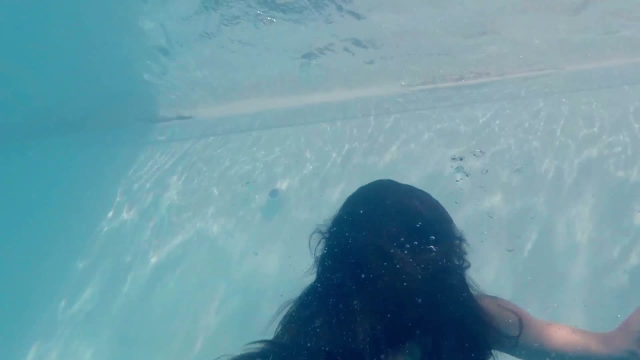 푸른 드레스를 입은 아름다운 여성이 물  ⁇ 에서 수영하고 있습니다.