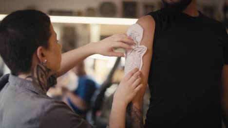 adult caucasian artist tries on a tattoo in the client's hand.