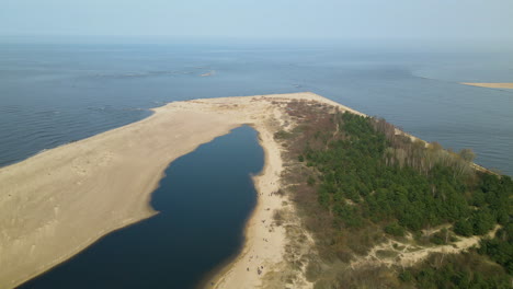drone flying sidewards showing beautiful sandy banks of vistula river entering in baltic sea, poland daytime sunny weather at mewia lacha nature reserve