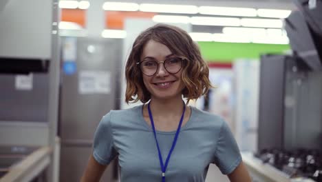 vendedora positiva o retrato de asistente de disparo en una tienda de supermercado. mujer con camisa azul y insignia mirando a la cámara y