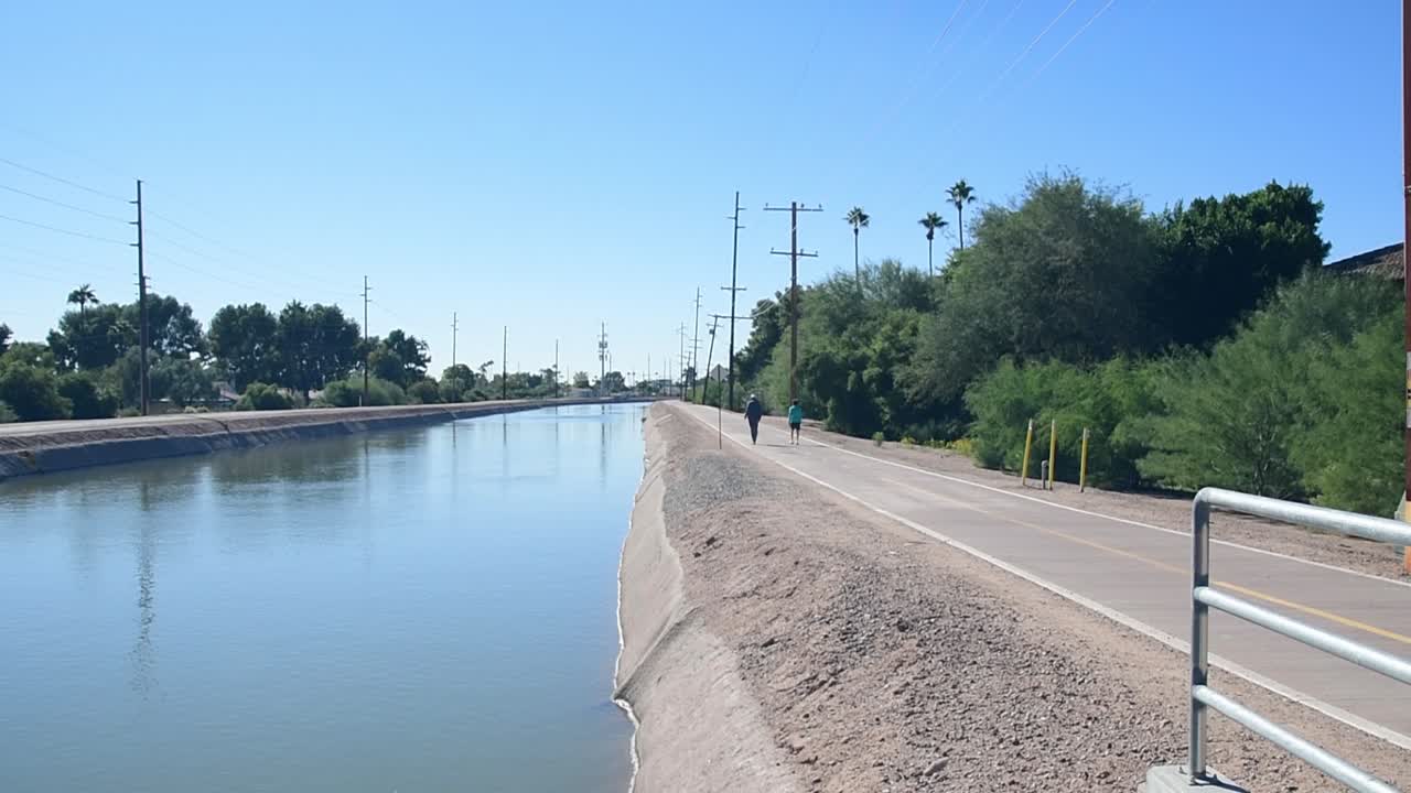 A couple practicing some sort of social distancing walks along the Arizona Trail Canal, Scottsdale, Arizona