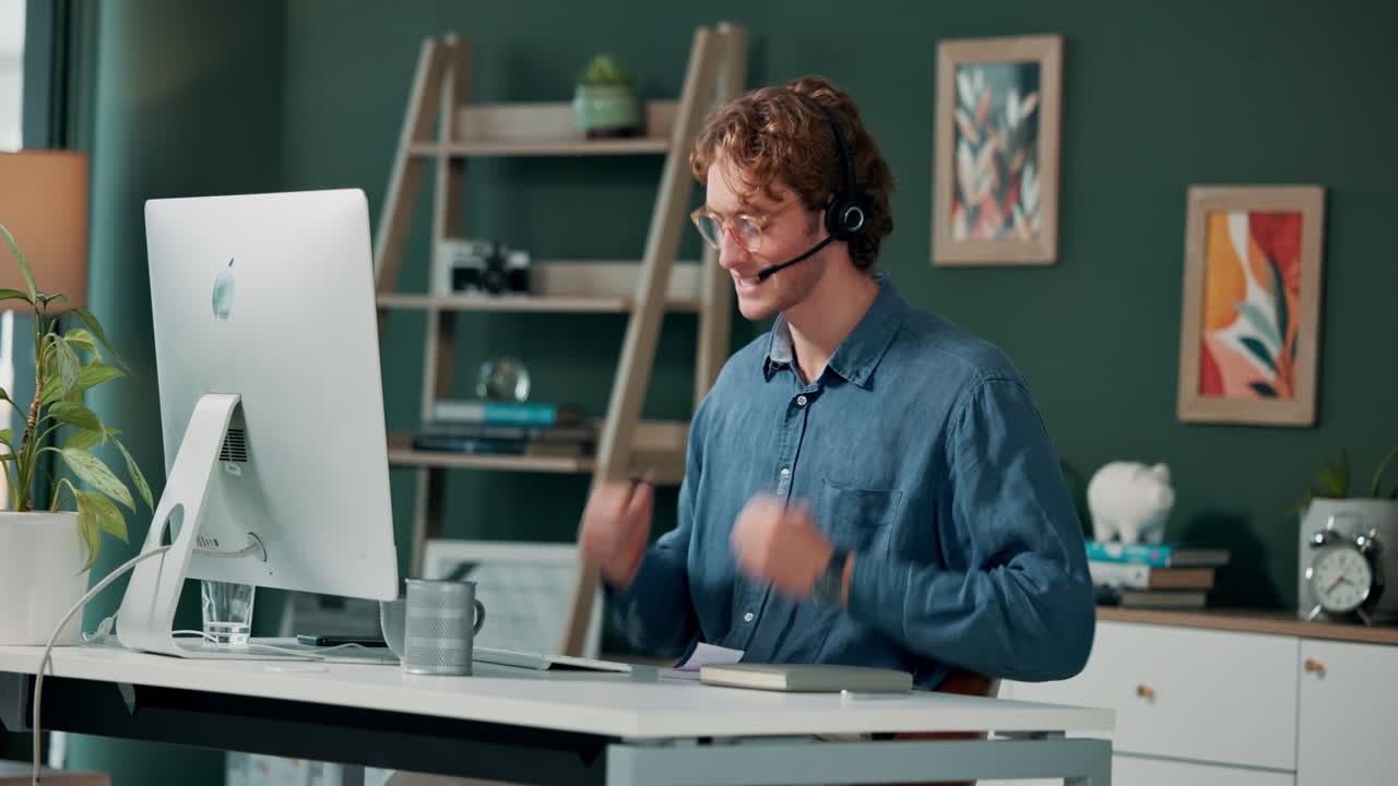Mand der arbejder ved et skrivebord med en computer og headset