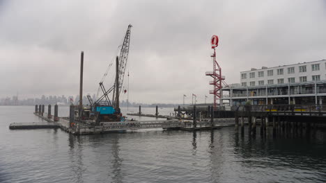 a commercial-sized boat, equipped with a crane, is docked in a harbor, with a hotel and sign visible in the background