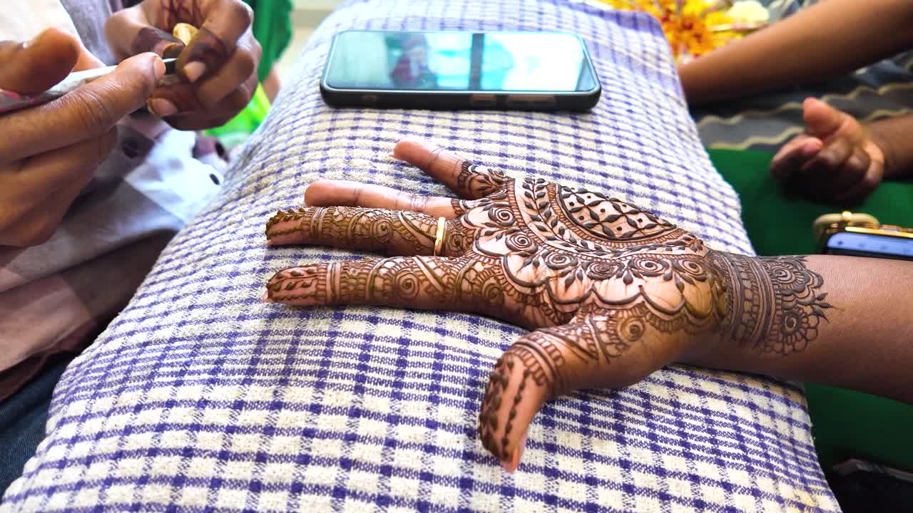 Artist Applying Intricate Henna Mehndi Design on a Woman's Hand