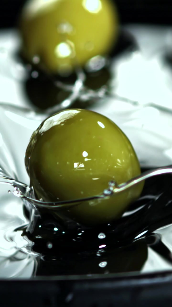 Al rallentatore di un'oliva verde che cade in un liquido con uno schizzo