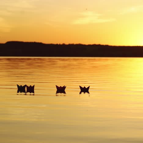 floating paper boats on the water at sunset. paper boat. origami.