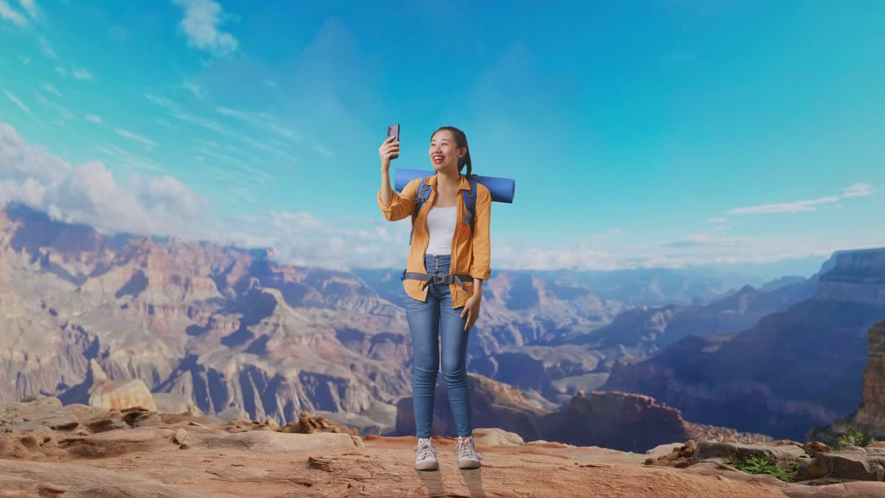 Full Body Of Asian Female Hiker With Mountaineering Backpack Waving Her Hand And Having A Video Call On Smartphone While Traveling At The Top Of Mountain