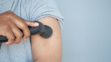 person using a handheld brush on their arm.