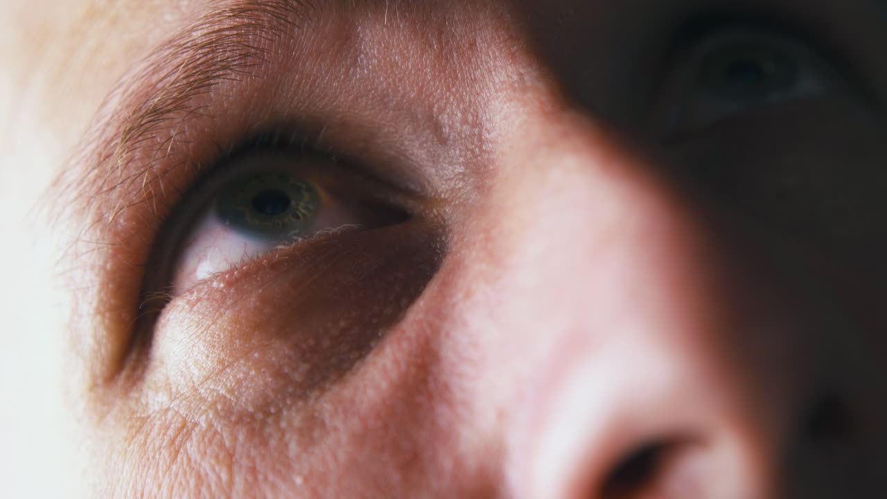 hombre con ojos verdes mira hacia arriba bajo una luz eléctrica brillante