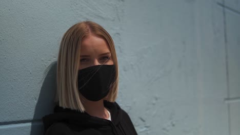 pretty blonde girl with face mask looking at camera, portrait, slow motion close up