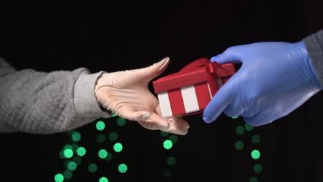 female hands in medical gloves give money in exchange for a red gift box. christmas shopping concept during quarantine