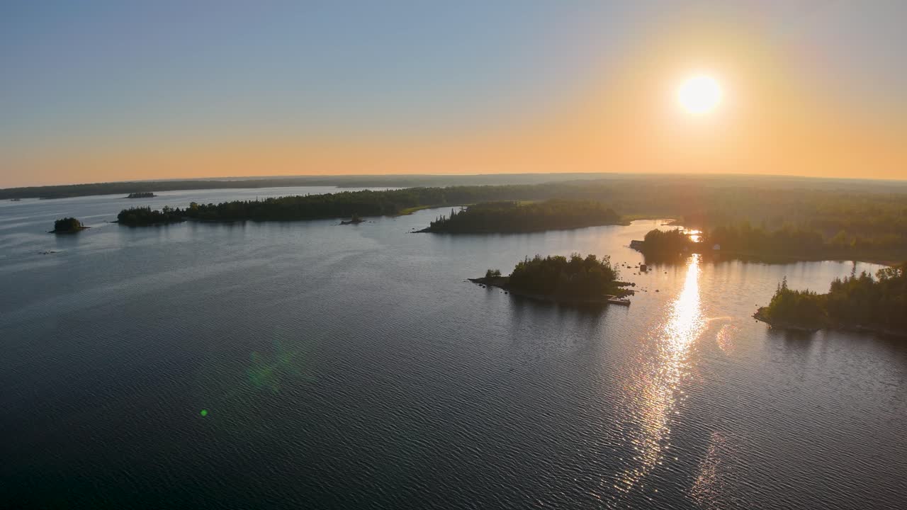 Vista aerea da drone del sole che tramonta sulle isole Les Cheneaux nella penisola superiore del Michigan, proiettando una luce dorata sul lago calmo e sulle isole boschive sparse