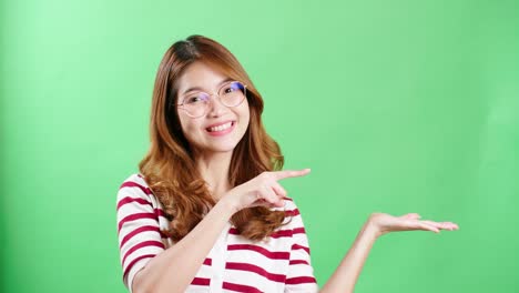 young woman in studio pointing to object to be graphically entered using chroma key