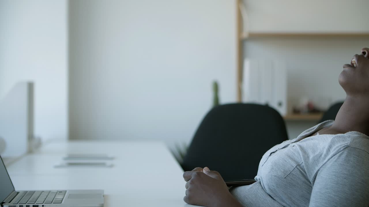Exhausted African American woman resting at workplace.
