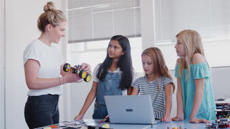 maestra con estudiantes mujeres construyendo y programando un vehículo robot en la clase de codificación de computadoras de la escuela