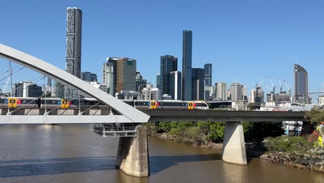 railway train crossing river through merivale bridge at brisbane city from northern side to southern side with downtown cityscape background, translink queensland rail, qld, australia