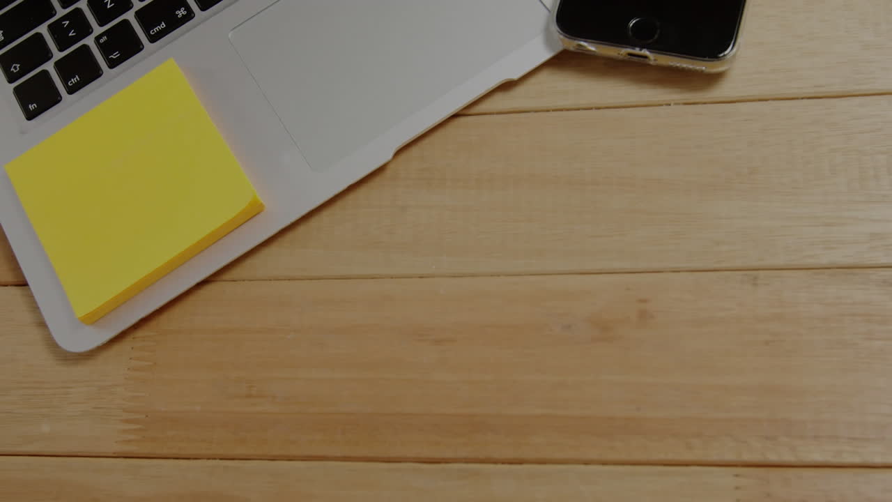 Animation of stock market data processing against close up of laptop and smarphone on table