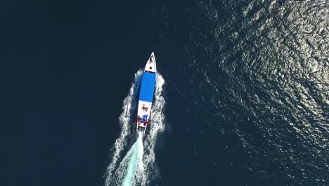 Aerial-view-Indonesian-boat-traveling-across-deep-blue-ocean,-tourist-summer-activity-in-Bali-Indonesia