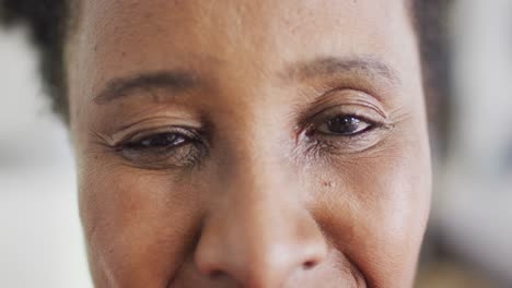 vídeo en primer plano retrato de la apertura de los ojos de una feliz mujer afroamericana sonriendo en casa, copia espacio